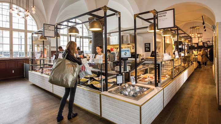 Da Coop skulle designe indretningen i Mad Cooperativets 800 kvadratmeter store butik, var udgangspunktet at gøre oplevelsen for de handlende helt unik. Alle standardløsninger blev smidt på porten, og der blev i stedet taget udgangspunkt i det fantastiske rum, som butikken ligger i. Den gamle ventesal på Københavns Hovedbanegård har søjler og et hvælvet loft. Bygningen er fredet, så i forbindelse med indretningen og lysinstallationen måtte der ikke bores i loft og vægge. Løsningen blev i stedet at anvende reoler. Coops konceptchef Caroline Fiedler valgte i samarbejde med Carsten Bahnsen, projektleder fra Philips, at anvende Københavner-armaturet med LED-lyskilde. De i alt 41 armaturer er monteret hængende fra midten af de mange reoler.