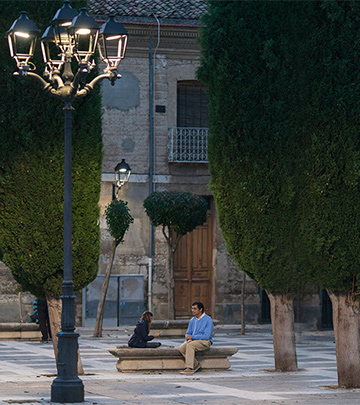 Mand og barn spiller kort på en gade i Palencia med Philips-belysning.
