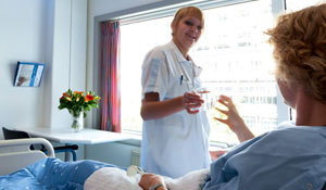 Sygeplejerske giver en patient et glas vand