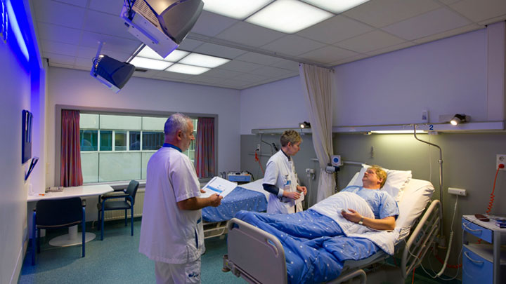 Læger, som behandler en patient i et rum, som er belyst med Philips HealWell-belysningssystemet