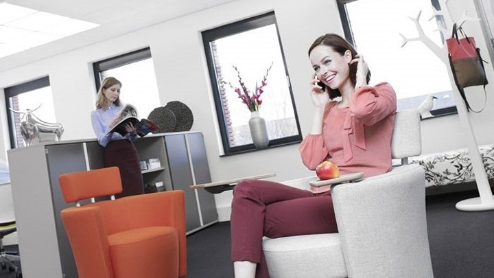 En kvinde taler i telefon under en Soundlight Comfort-løsning. Ideel kontorbelysning med fokus på de ansattes trivsel.