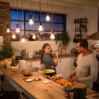 Par taler under Philips vintage LED pærer, som hænger ned fra loftet og skaber en varm hyggelig glød