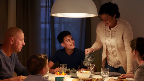 Familie spiser aftensmad i et hjem ved et godt oplyst spisebord