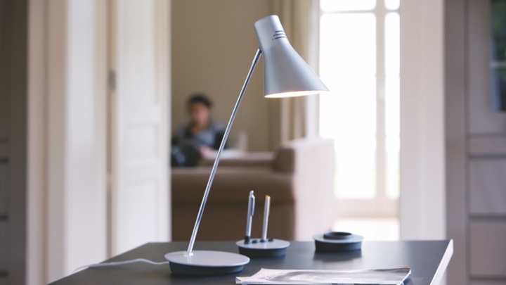 En bordlampe på et skrivebord, som peger på blyant og papir