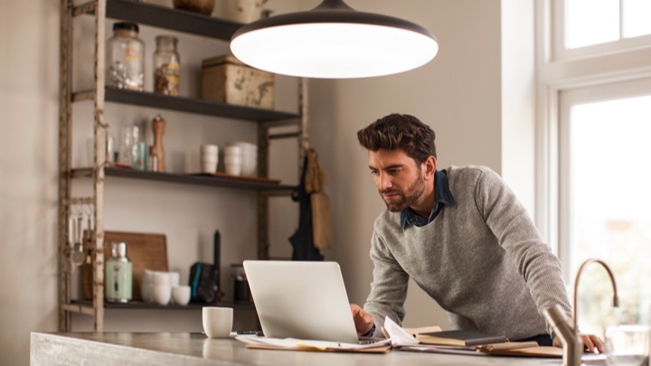 En mand arbejder hjemme under en smart lampe