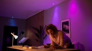 Intelligente Philips Hue LED lys skaber en levende lilla og lyserød stemning i stuen og viser, hvordan man kan tilpasse stemningsbelysningen til filmaftener og afslapning i moderne hjem.